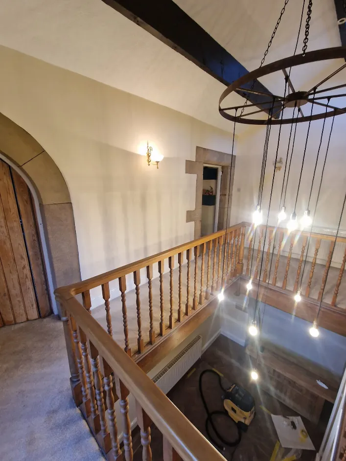 Painted walls around a stone archway and oak door under exposed beams