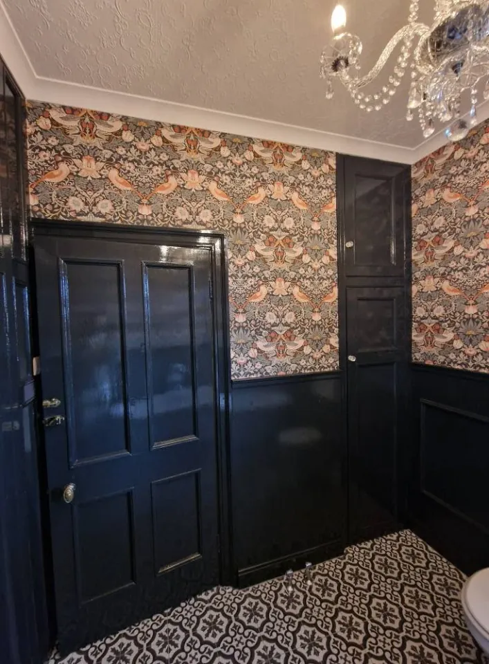 Navy gloss doors and panelling beneath a patterned wallpaper