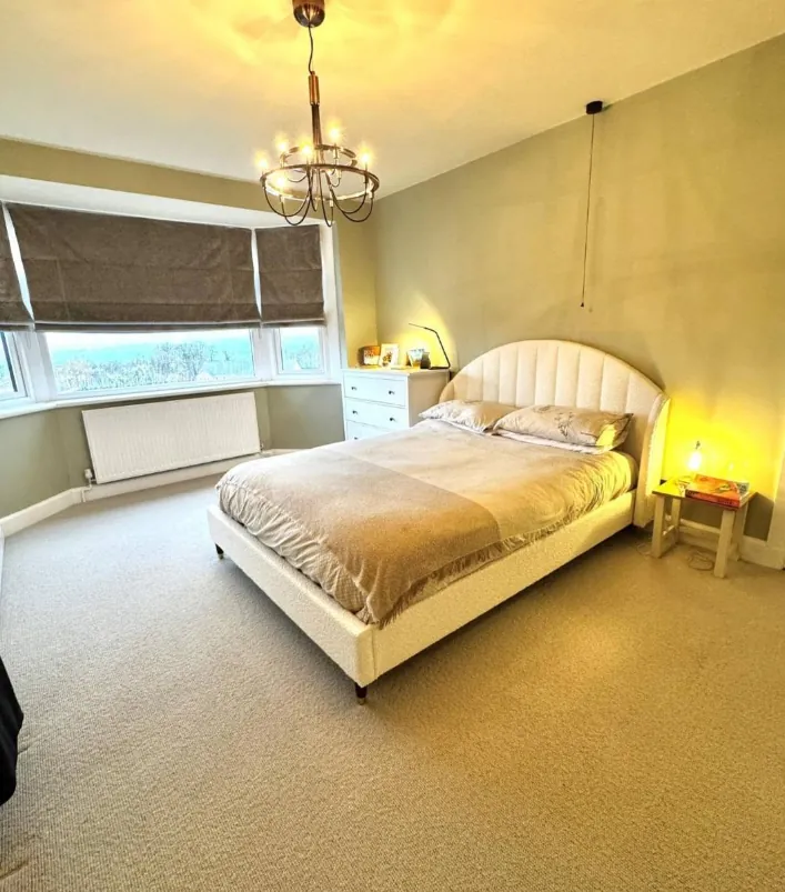 Bedroom with sage green walls, a bay window and a chandelier