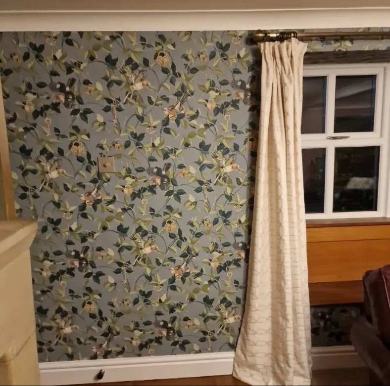 Cottage room papered in a blue green bird and leaf wallpaper