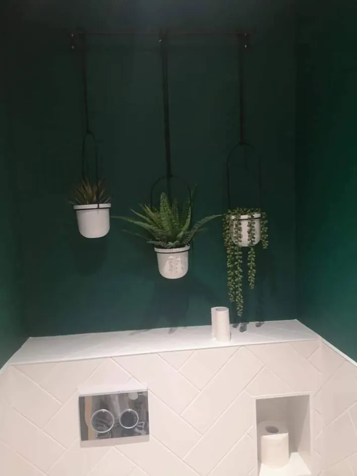 Cloakroom painted forest green above white herringbone tiles