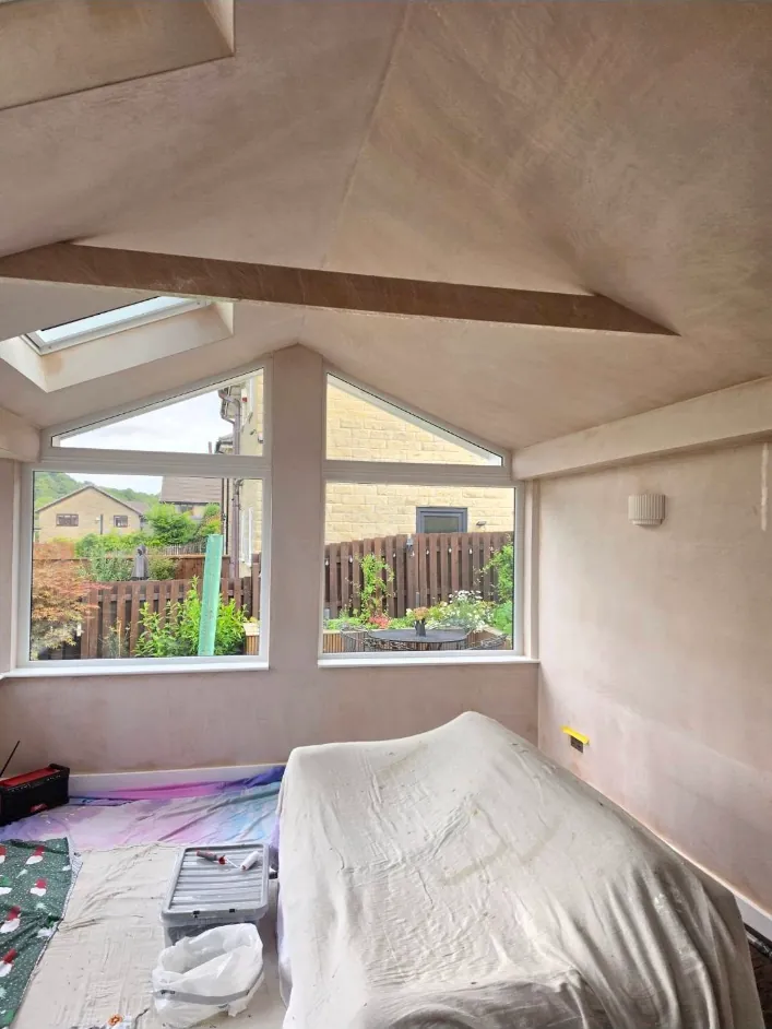 The same conservatory before, bare plaster with furniture under dust sheets
