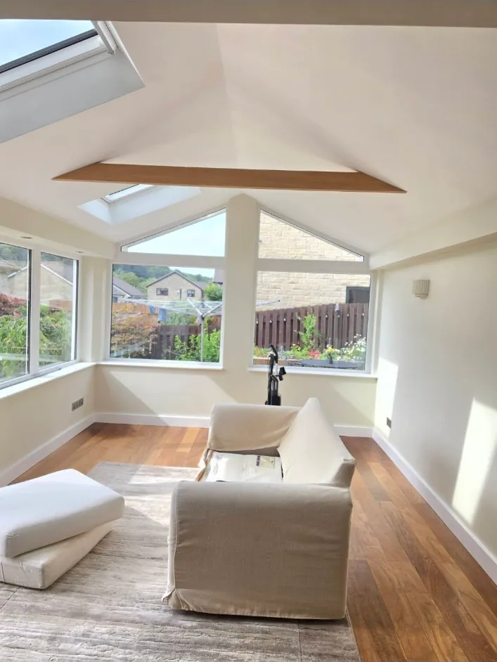 Conservatory with a vaulted ceiling and walls painted soft white around an oak beam
