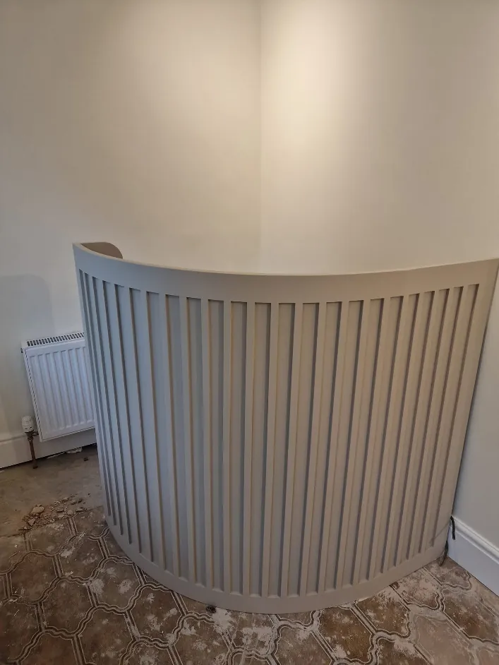 Curved slatted radiator cover painted soft grey
