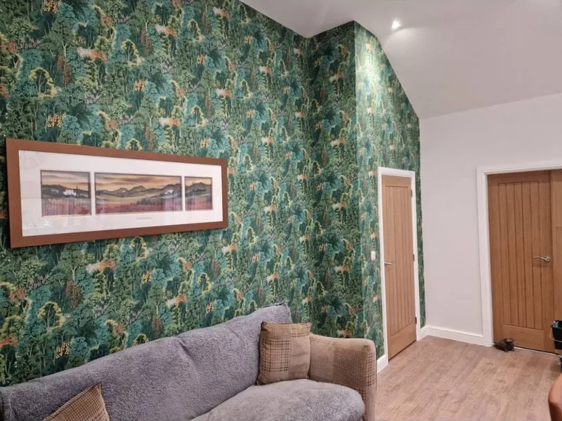 Living area with a dense green forest print wallpaper and oak doors