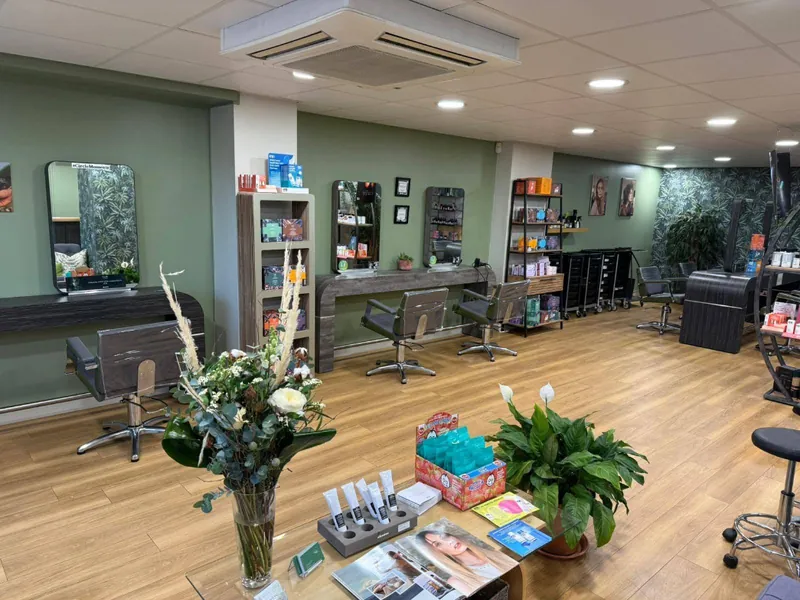 Hair salon painted sage green with a botanical wallpaper end wall