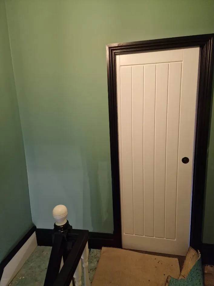 Green hallway wall with a white door set in a black frame