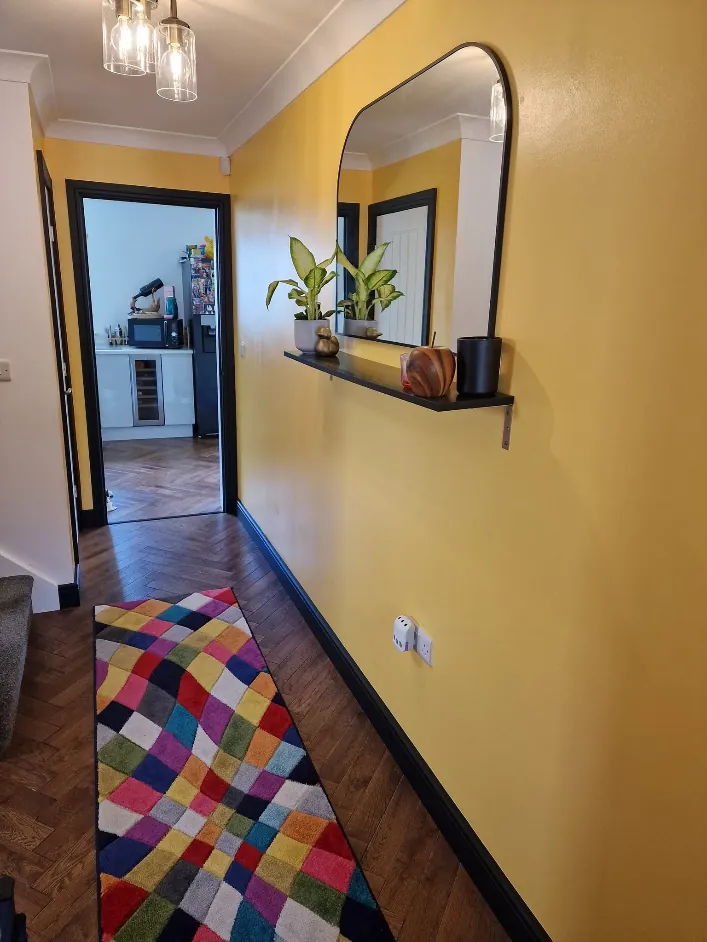 Hallway painted ochre yellow with black skirting and frames