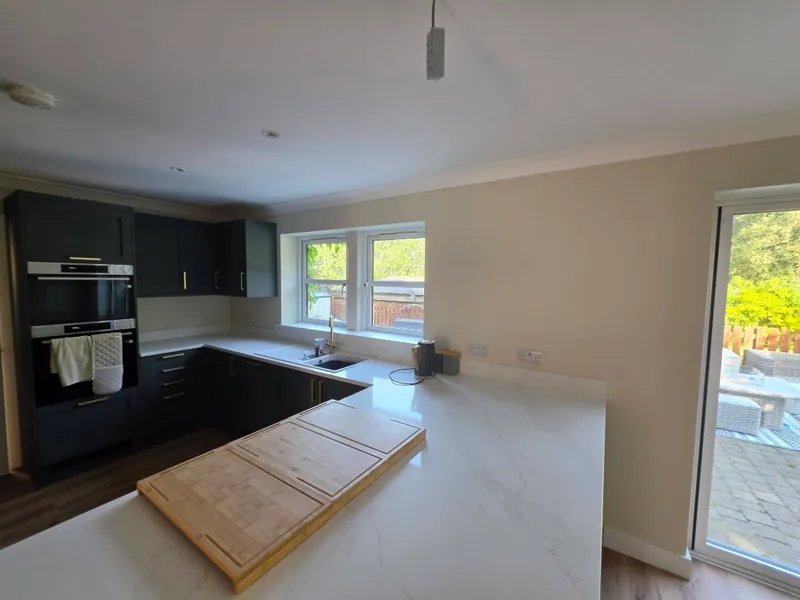Kitchen with cream walls, white ceiling and dark green shaker units