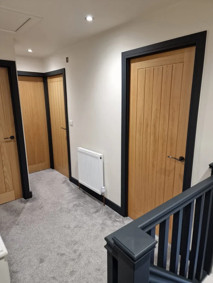 Landing with oak doors set in charcoal painted frames and a charcoal balustrade