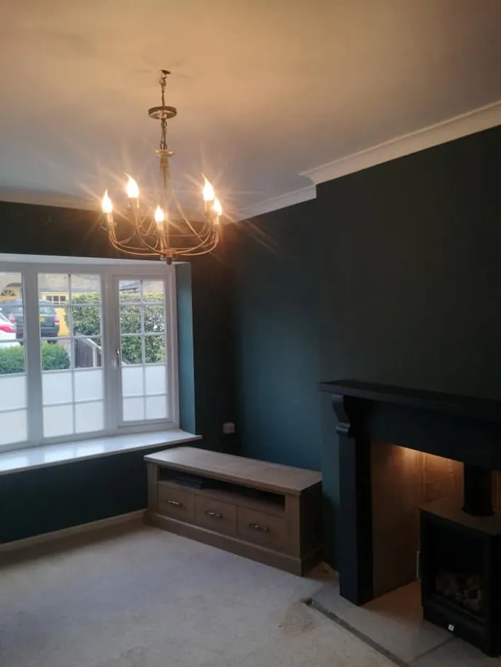 Living room painted deep teal with a matching fire surround
