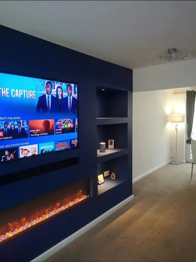 Living room media wall painted deep navy around a wall fire and TV