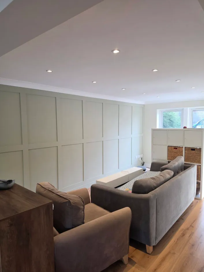 Living room with full width wall panelling in pale sage and a white ceiling