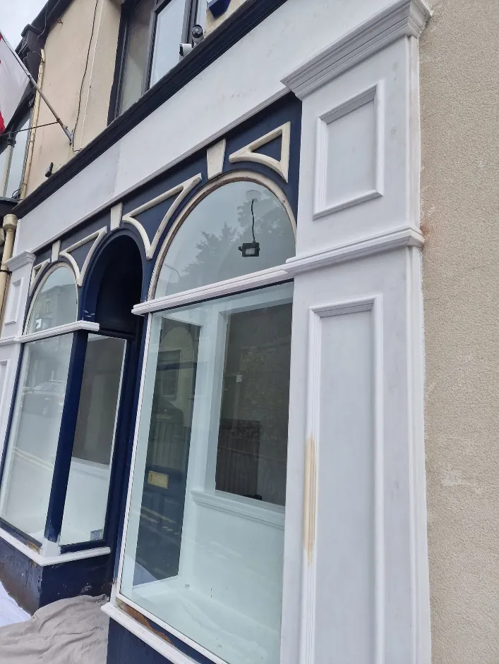 The same shopfront before, navy and white paint flaking and weathered