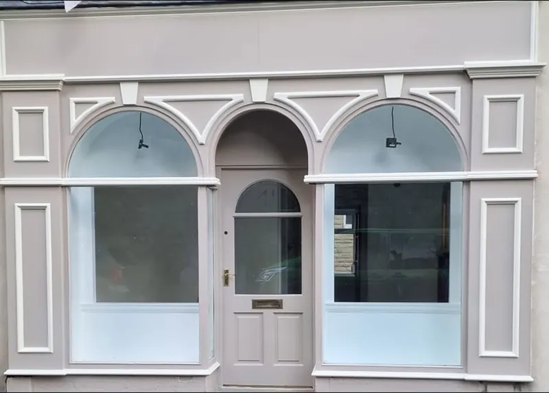 Victorian style arched shopfront repainted in warm taupe with white details