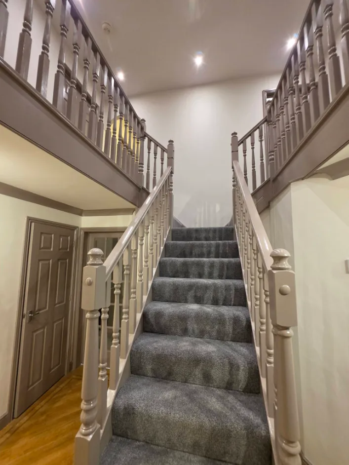 Double staircase and gallery landing finished in taupe gloss with cream walls