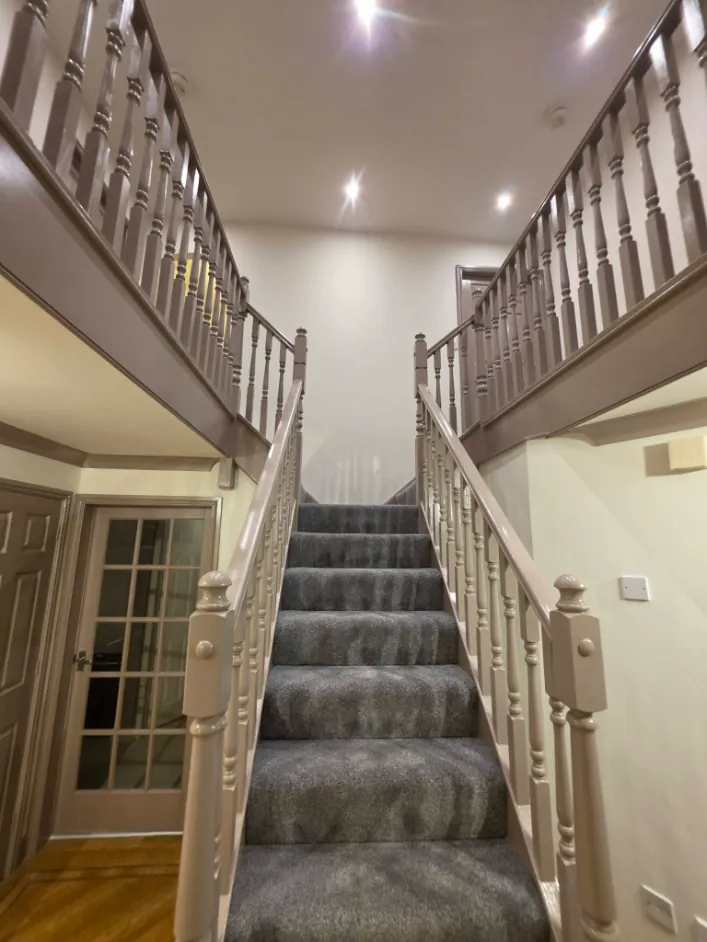 Hallway staircase with spindles and handrail repainted in a soft taupe and cream walls