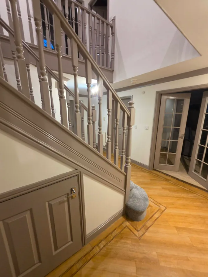 Understairs cupboard door and panelling painted taupe beside a hardwood floor