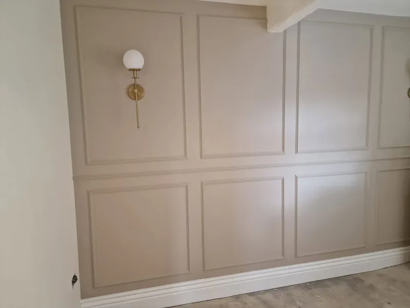 Full height wall panelling painted a soft mushroom with brass wall lights